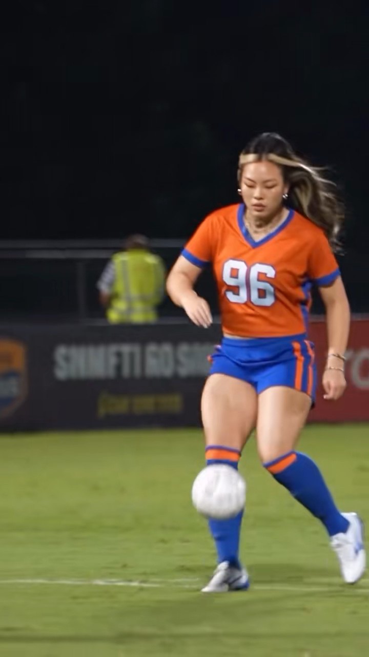 Unretouched video poster showing the orange-shirt scorer and football